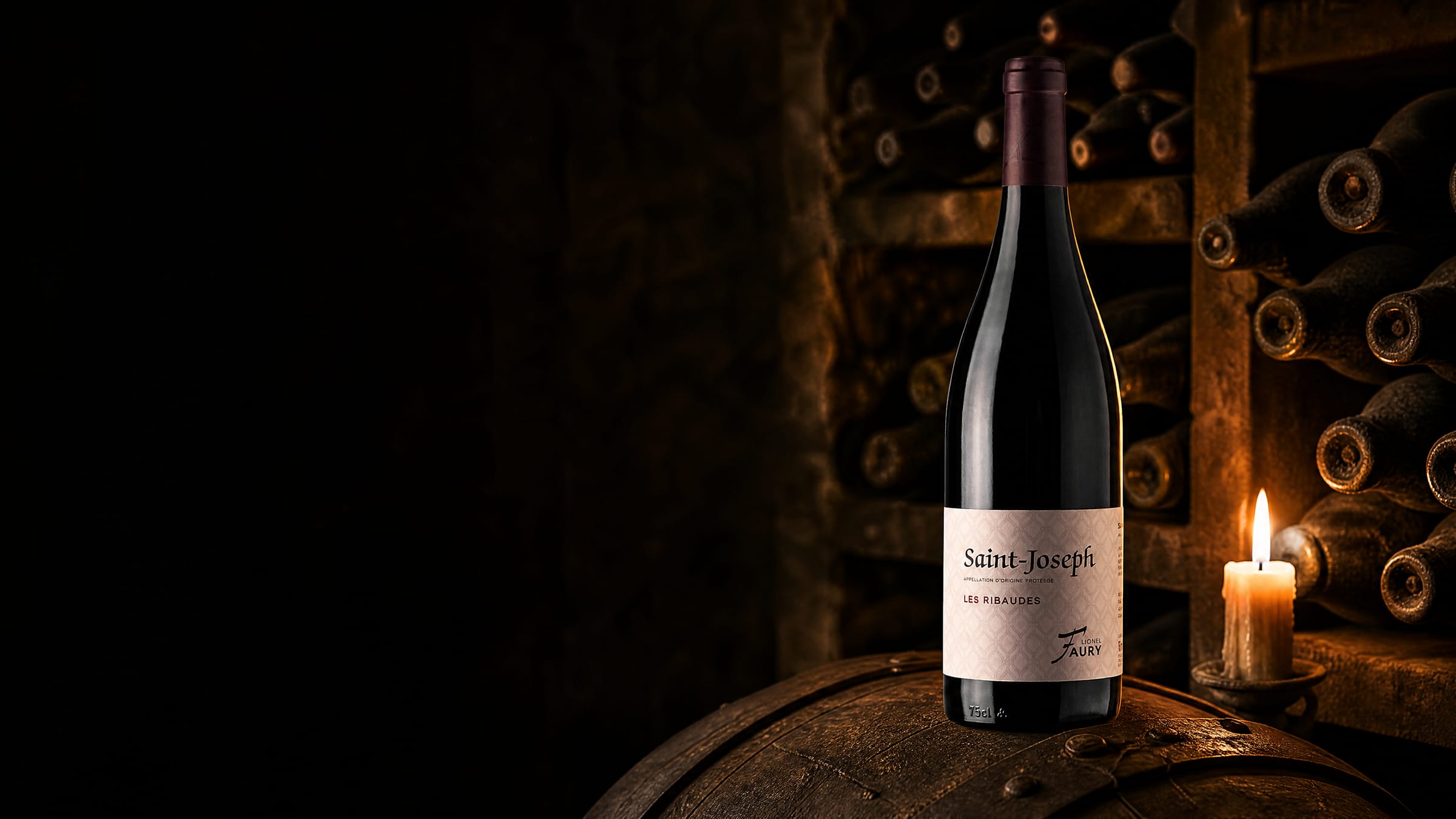 The Faury Saint-Joseph bottle lit by candlelight on an oak barrel in a dark cellar