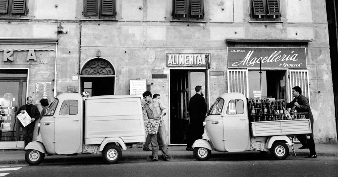 Black and white photograph of a vintage delivery van outside a wine shop