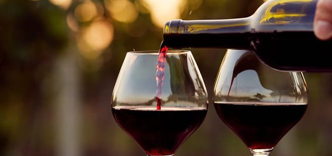 Red wine poured into glasses against low evening sun
